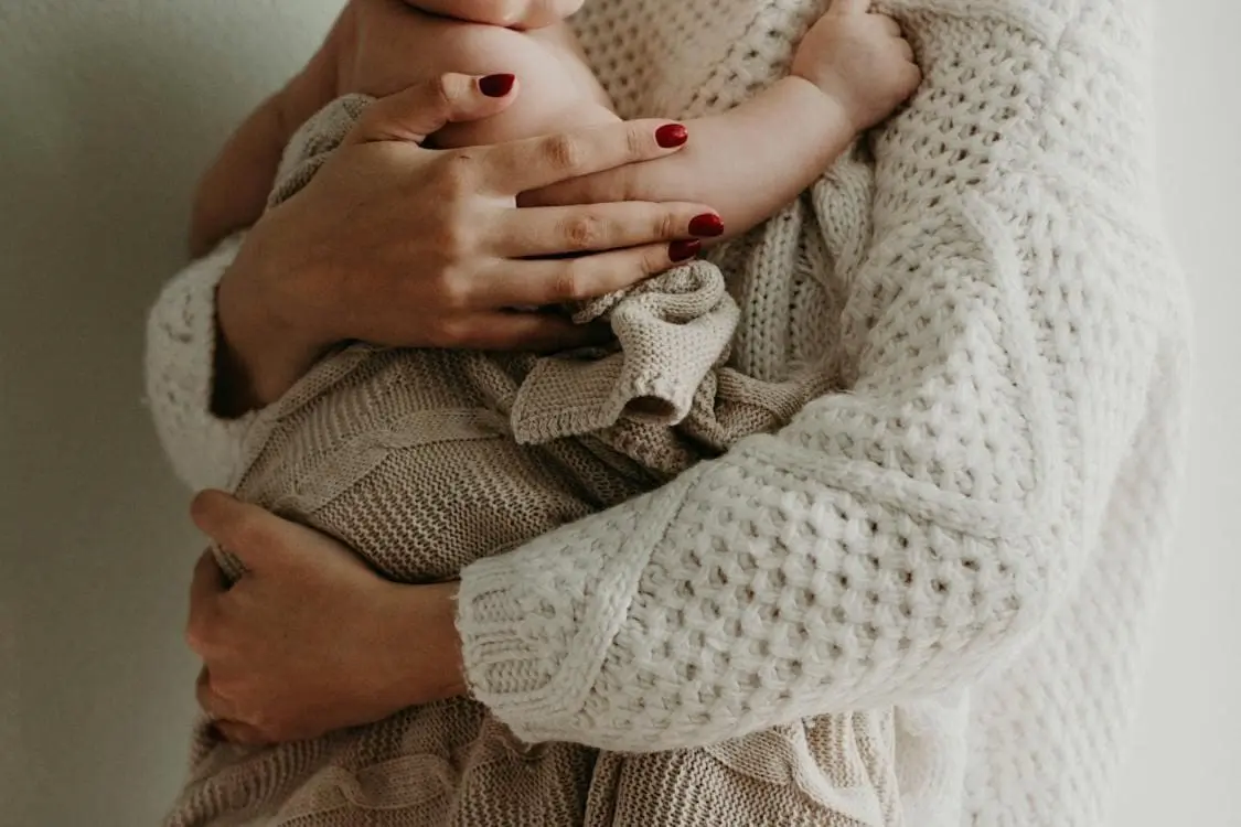 A woman with painted nails holding her baby