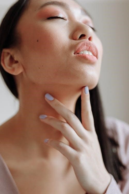 A woman with black hair touching her chin and neck